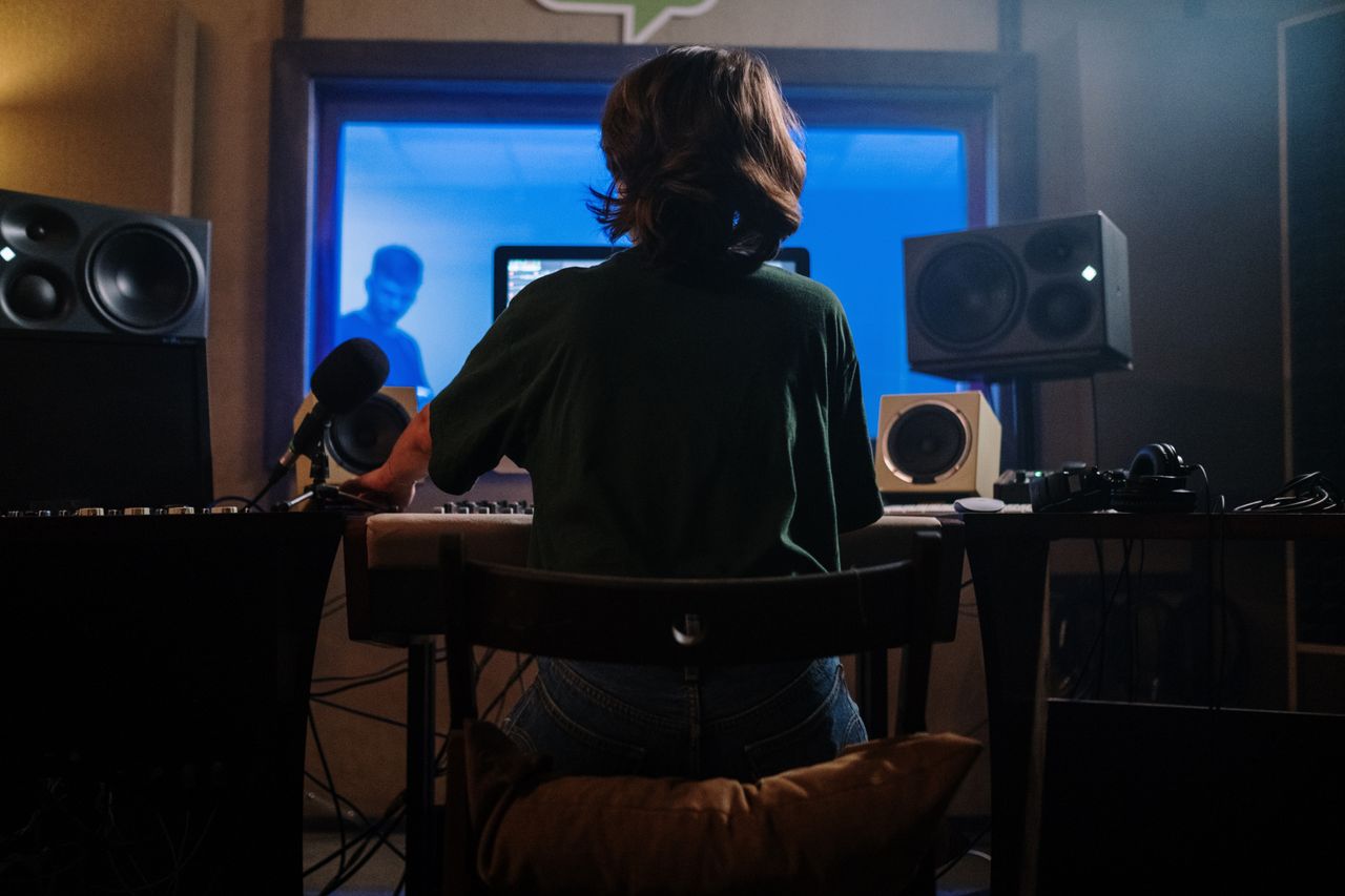 The Art of Drawing Readers In: Your attractive post title goes here A music producer works in a sound studio with microphones and speakers, creating audio content.